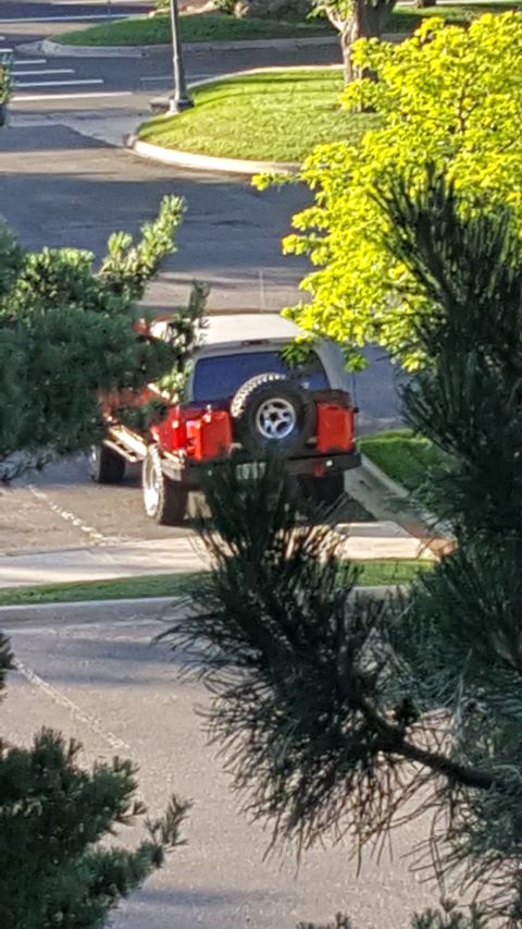 1996 Ford Bronco - Rear view of a red SUV, equipped with a spare tire and two red fuel cans mounted on the back.