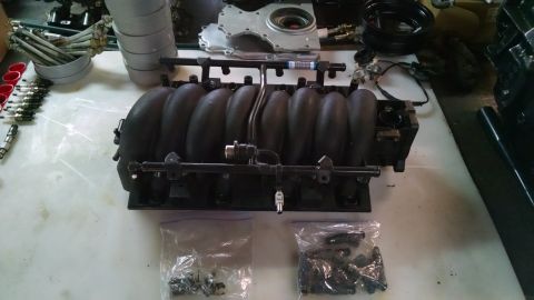 1985 Jeep CJ7 - Engine intake manifold and associated parts laid out on a workbench.