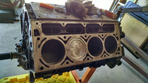 1985 Jeep CJ7 - Engine block on stand, showing cylinder bores and a piston. Tools are present on the top surface.