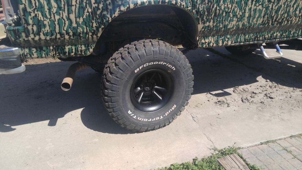 1991 Ford Bronco with camouflage paint, large off-road tires, and a visible exhaust pipe