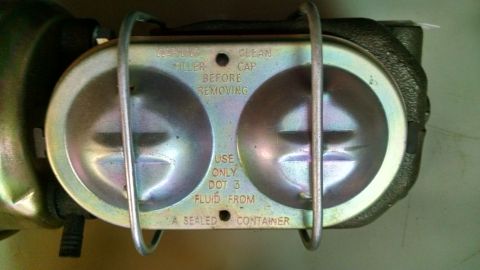 1985 Jeep CJ7 - Close-up of a brake master cylinder reservoir, showing fluid level indicators and instructions.