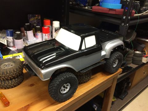 1989 Ford Bronco - A remote-controlled model truck sits on a wooden surface, surrounded by hobby supplies.