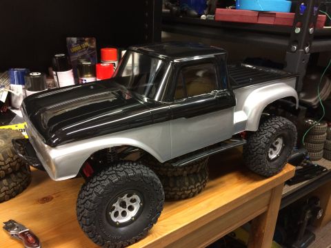 1989 Ford Bronco - RC pickup truck model with black top and silver body is displayed on a wooden surface.