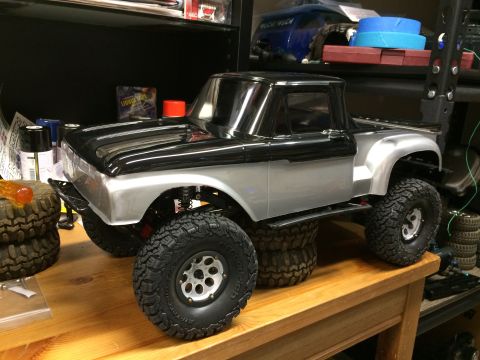 1989 Ford Bronco - A detailed remote-controlled truck model is displayed on a workbench, surrounded by spare parts and tools.