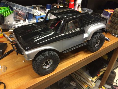 1989 Ford Bronco - RC truck model with off-road tires sits on a workbench with hobby supplies.