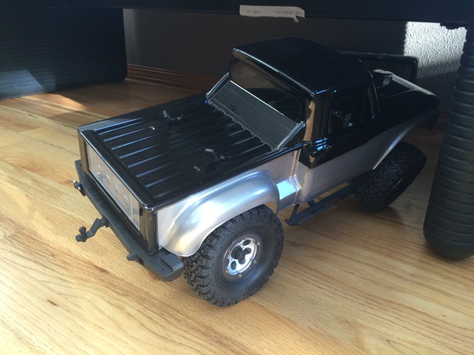 Black and silver toy truck with off-road tires on a wooden floor