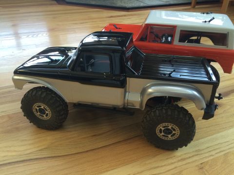 1989 Ford Bronco - Two remote-controlled trucks, a pickup and an SUV, are positioned on a wooden floor.