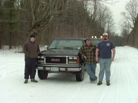 1978 Ford Bronco - Three men pose with two GMC trucks in a snowy, wooded landscape.