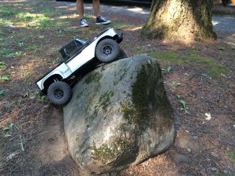 1989 Ford Bronco - RC rock crawler truck navigating a large boulder on a dirt path.