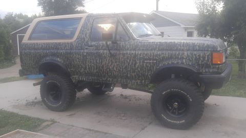 1991 Ford Bronco - Side view of a 1991 Ford Bronco, modified with a camouflage wrap and off-road tires.