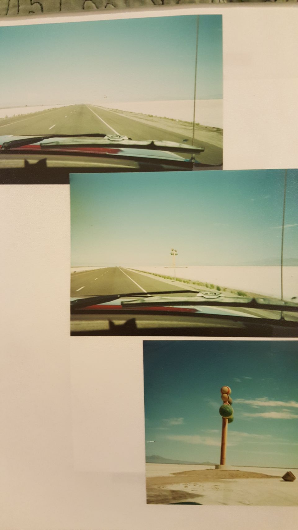 Dashboard view of a long, straight highway stretching to the horizon under a clear blue sky