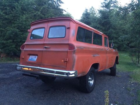 1962 Chevrolet Suburban - This orange panel van features a custom spoiler and chrome bumper, seen from the rear.