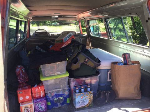 1962 Chevrolet Suburban - The rear of a vehicle is filled with various items for a trip, including coolers and beverages.