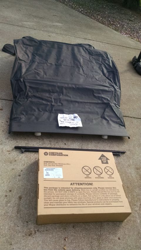 1985 Jeep CJ7 - A black soft top is laid out next to a box labeled 'Chrysler Corporation' containing soft top quarter windows.