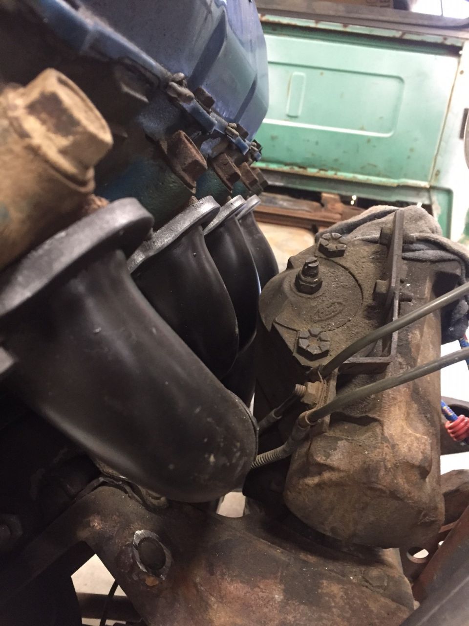 Close-up of engine exhaust manifold and rusty engine components