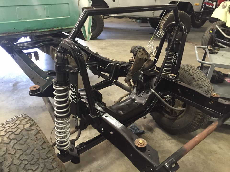 Custom roll cage and Fox shocks on a vehicle frame.