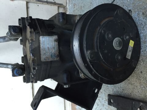 1989 Ford Bronco - Photograph of an automotive AC compressor showing the clutch pulley and a small manufacturer ID label.