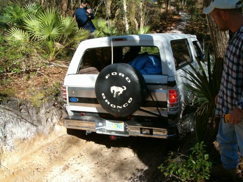 1991 Ford Bronco - Ford Bronco navigating a rough dirt path with people watching.