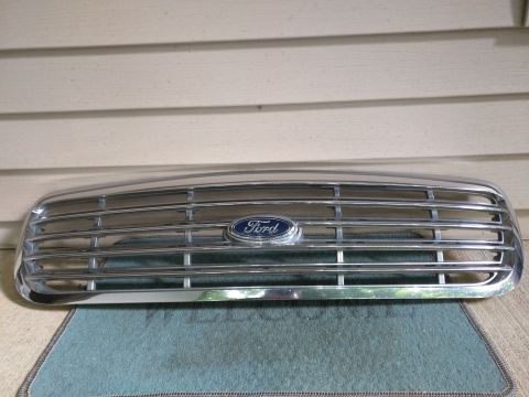 2007 Ford Crown Victoria - A chrome Ford grille with the Ford oval logo is shown in a front-facing view. The grille is mounted horizontally and appears to be a replac…