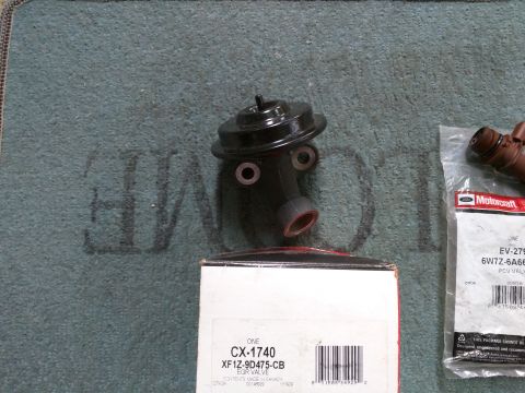 2007 Ford Crown Victoria - A black EGR valve is shown in the center of the image, with a Motorcraft PCV valve and its packaging to the right. A white box with part in…