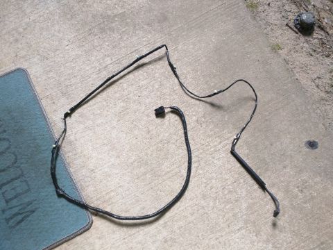 2007 Ford Crown Victoria - A black wiring harness with a black connector is laid out on a concrete surface next to a blue welcome mat. The harness appears to be a veh…