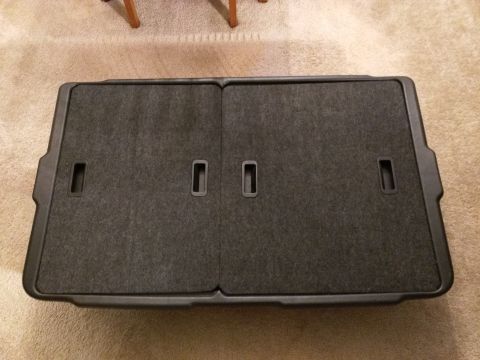 2007 Ford Crown Victoria - A folded cargo cover for the trunk of a car is shown lying on a carpeted floor. The cover is dark gray with black plastic trim and two rece…