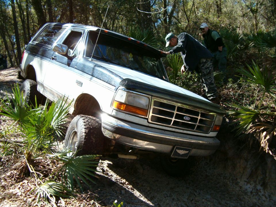 White and dark blue Ford Bronco off-roading, front view