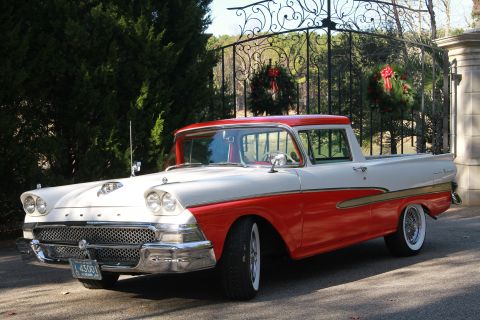 1958 Ford Ranchero - This classic pickup truck features a distinctive two-tone paint scheme and is parked near a decorative gate adorned with holiday wreaths.