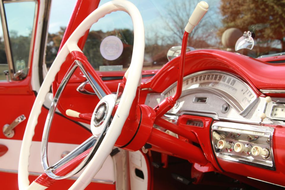 Red and white steering wheel and dashboard of a 1957 car interior