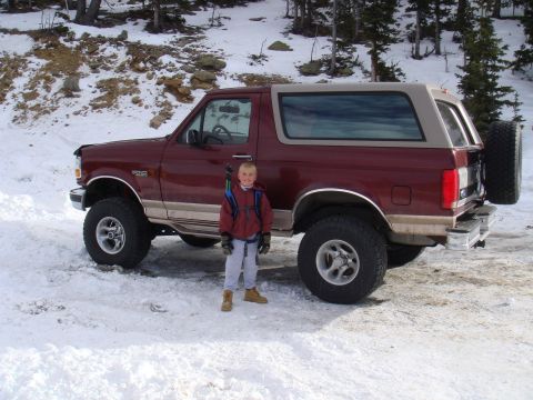 1996 Ford Bronco - A child poses in front of a maroon and tan 1996 Ford Bronco in a snowy, wooded area.