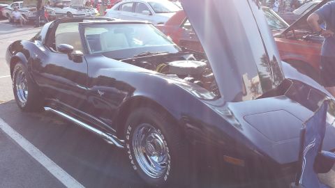 1976 Ford Ranchero - A dark Chevrolet Corvette C3 is displayed with its hood open, revealing the engine bay.
