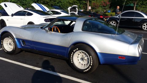 1976 Ford Ranchero - A two-tone silver and blue 1976 Chevrolet Corvette is parked in a lot with other vehicles.