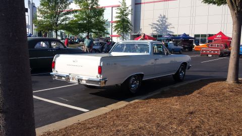 1976 Ford Ranchero - A light-colored Chevrolet El Camino is parked at an outdoor event with other vehicles and tents in the background.