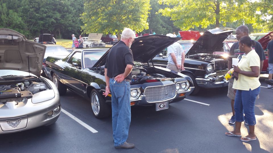 Black Ford Ranchero with hood open, grille visible, parked at car show