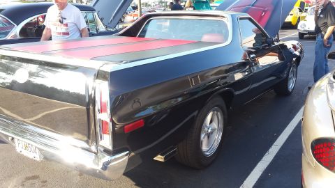 1976 Ford Ranchero - Rear 3/4 view of a black 1976 Ford Ranchero, a red tonneau cover and custom wheels.