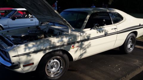 1976 Ford Ranchero - White coupe with black racing stripes and hood open, parked next to a silver car.