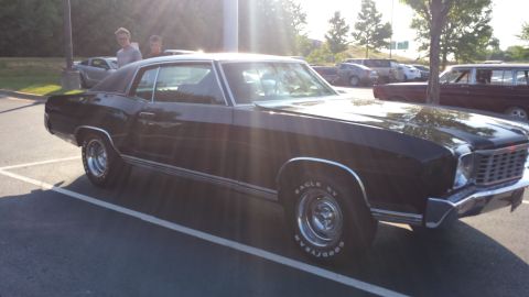 1976 Ford Ranchero - A black Chevrolet Monte Carlo is parked in a lot with other vehicles visible.