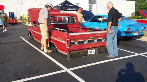 1976 Ford Ranchero - A red Ford pickup truck is parked next to a blue car, with people examining the vehicles.