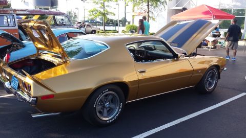 1976 Ford Ranchero - This gold coupe, likely from the early 1970s, is displayed with both its hood and trunk open, revealing racing stripes on the hood.