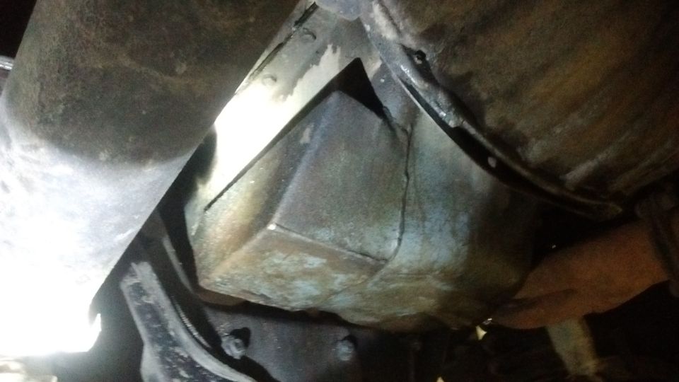 Underside of a vehicle, showing a metal component and exhaust pipe