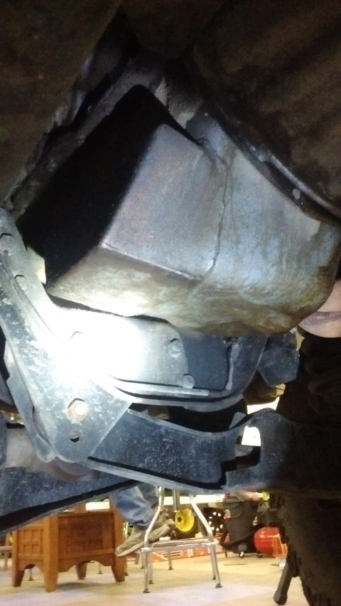 1985 Ford Bronco - Undercarriage view of a vehicle's suspension and drivetrain components, with a large metal casing visible.