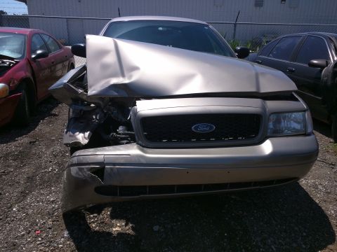 2007 Ford Crown Victoria - A heavily damaged 2007 Ford Crown Victoria sits in a lot, its front end crushed from an accident.