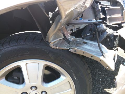 2007 Ford Crown Victoria - Close-up of a heavily damaged car fender and wheel, showing bent metal and structural components.