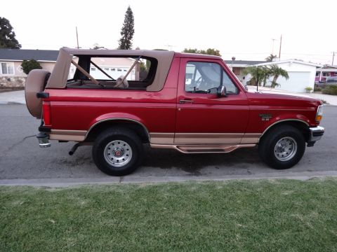1994 Ford Bronco - This 1994 Ford Bronco is shown from the side, a red exterior and a tan soft top.