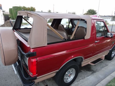 1994 Ford Bronco - This red SUV features a removable tan soft top, exposing the interior and rear cargo area.