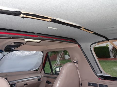 1994 Ford Bronco - The interior of a red SUV is visible, with tan seats and dashboard components.