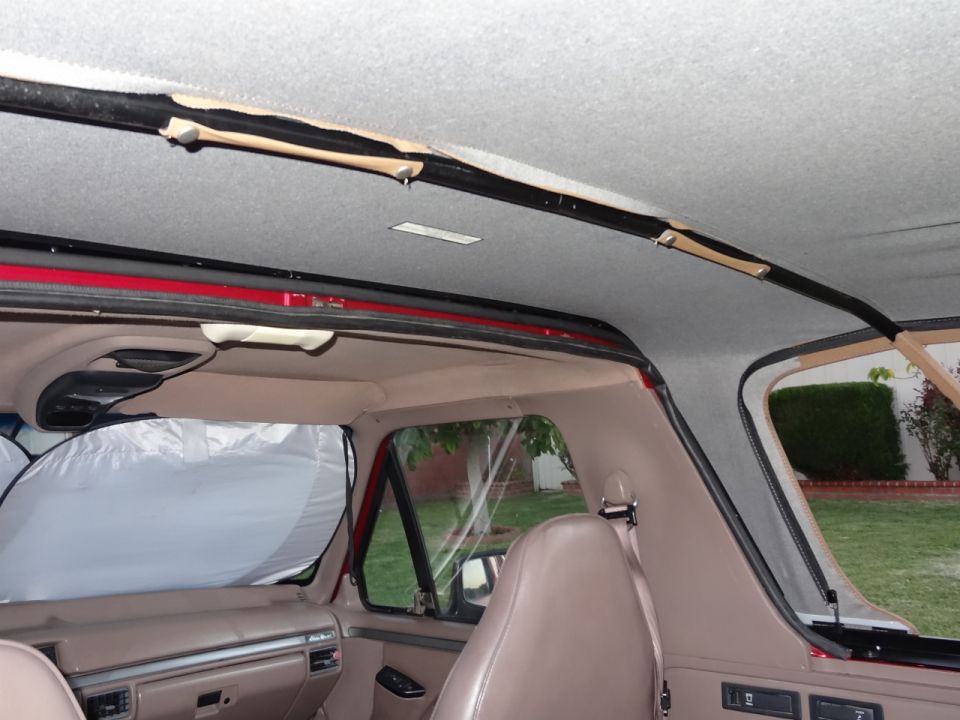 Interior of a red SUV showing tan seats, dashboard, and headliner with visible wear