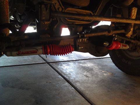 1996 Ford Bronco - A close-up view of the steering stabilizer and suspension components on the underside of a vehicle.
