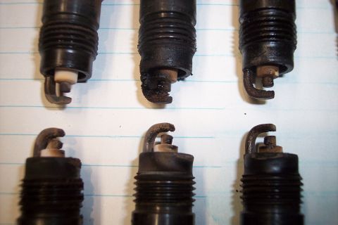 1990 Ford Bronco - Close-up of several used spark plugs, showing varying degrees of wear and fouling.