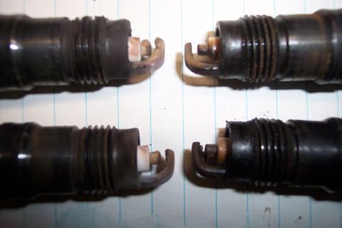 1990 Ford Bronco - Four used spark plugs are shown on lined paper, with the top two and bottom two in focus respectively.
